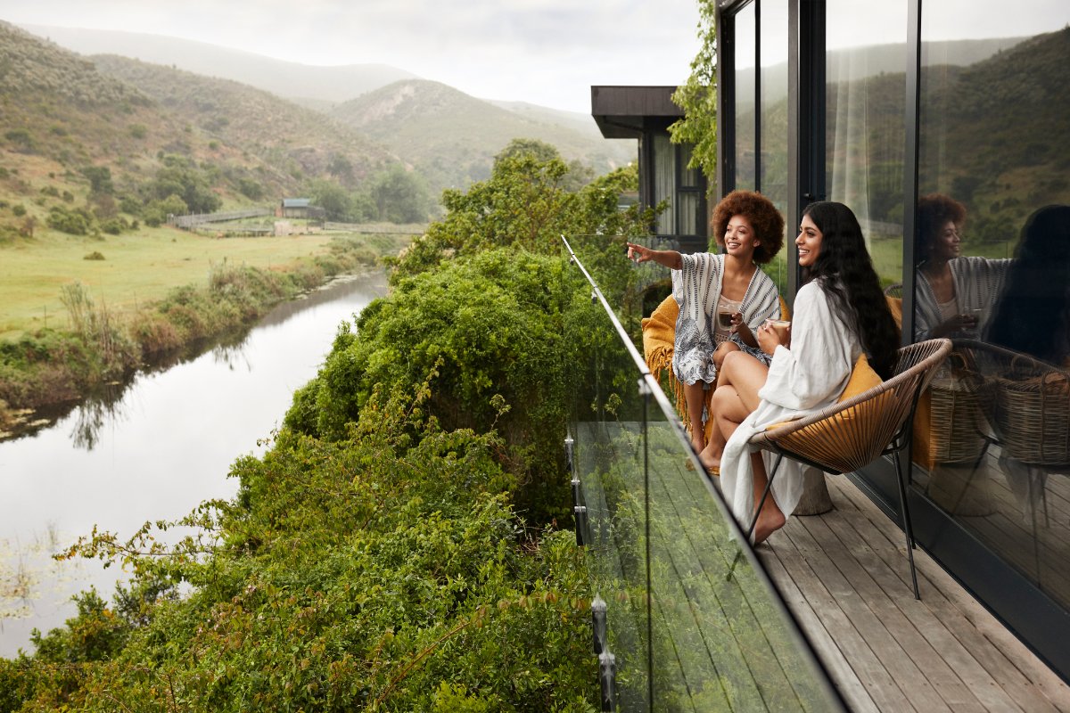 Travellers on a balcony overlooking a green river valley