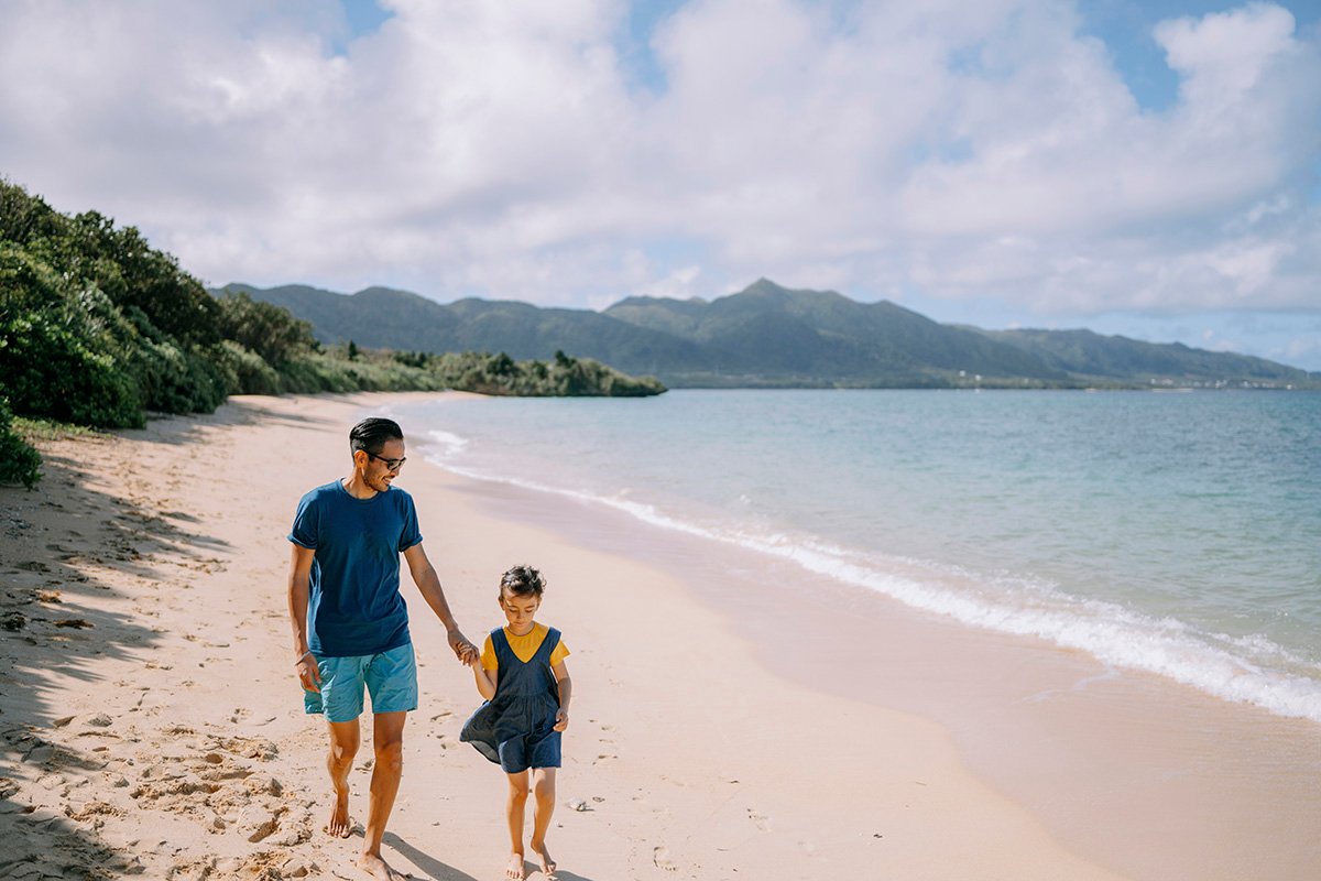 Parent and child walking on a tropical beach